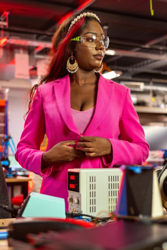African American female engineer in a vibrant workspace wearing protective goggles.