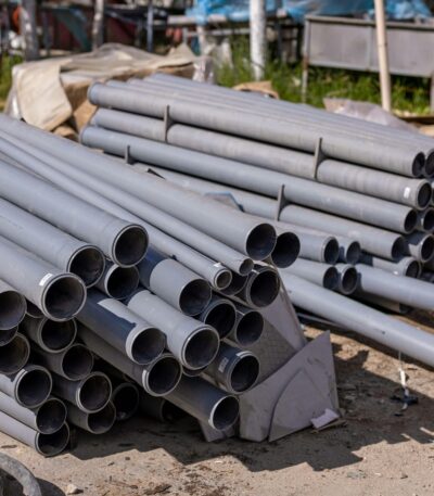 A collection of gray PVC pipes neatly stacked at an outdoor construction site.